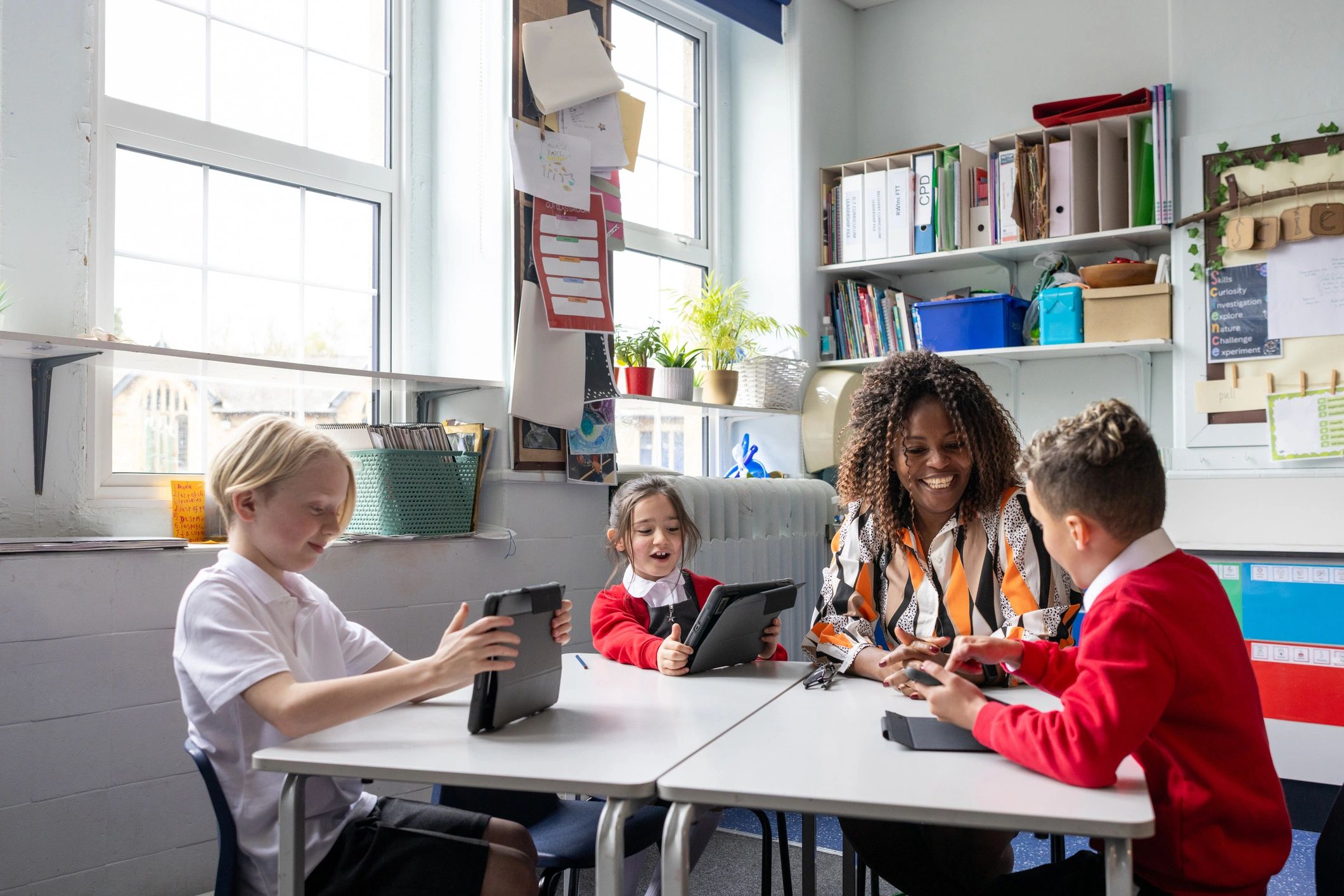Teacher supporting students using tablets in a classroom