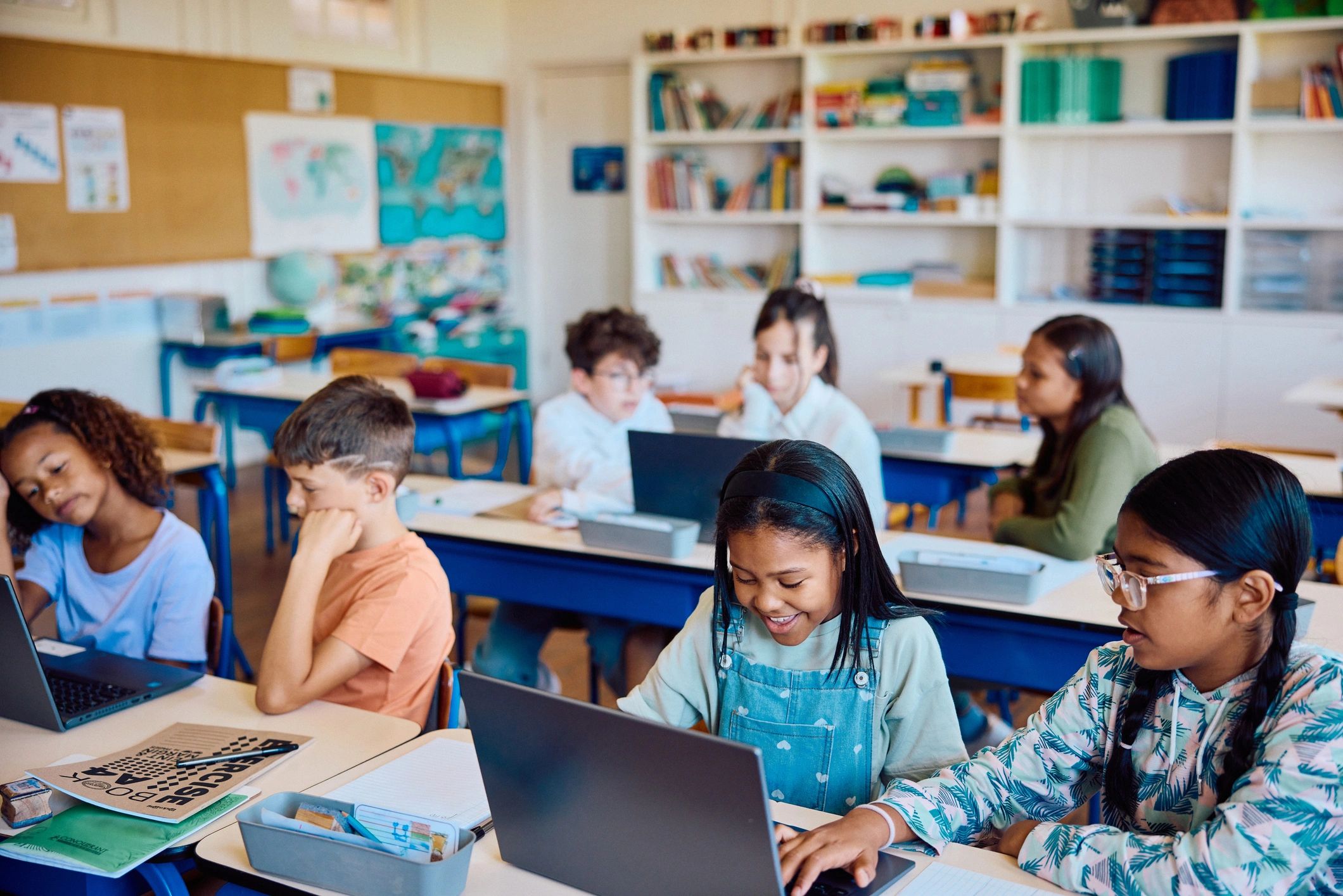Children using a laptop together in a bright preschool classroom